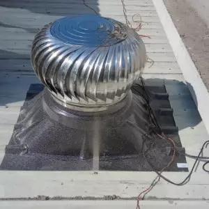 Roof Ventilator Installed On Industrial Building Roof Against Clear Blue Sky