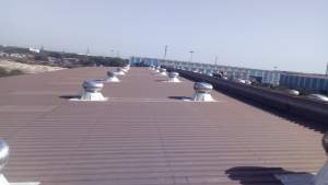 Wind Turbine Ventilator Installed On Factory Rooftop Showing Spinning Blades Against Cloudy Sky